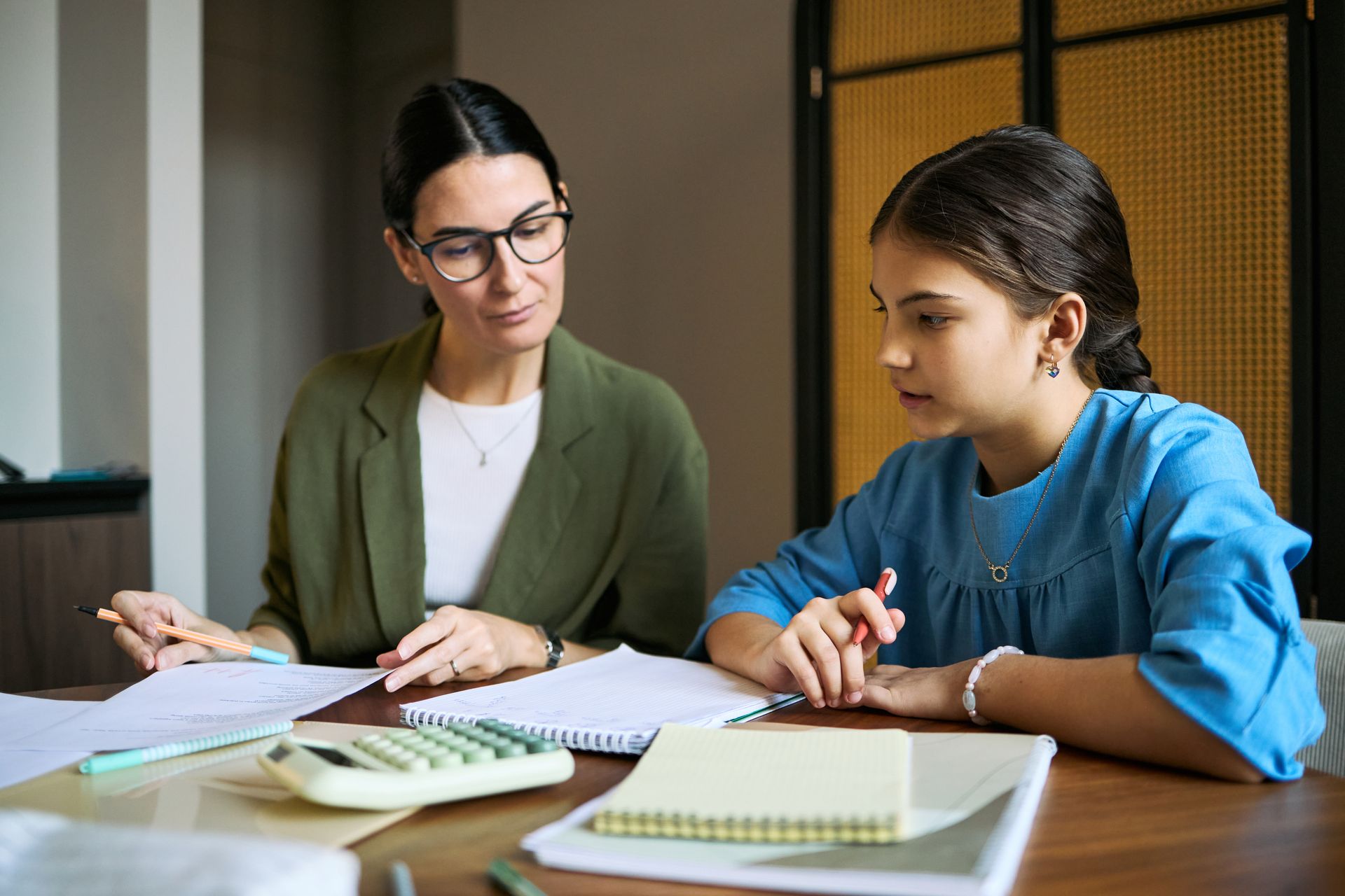 Middle aged woman tutoring schoolgirl, reviewing homework and explaining math at desk. Middle aged woman tutoring schoolgirl, reviewing homework and explaining math at desk.