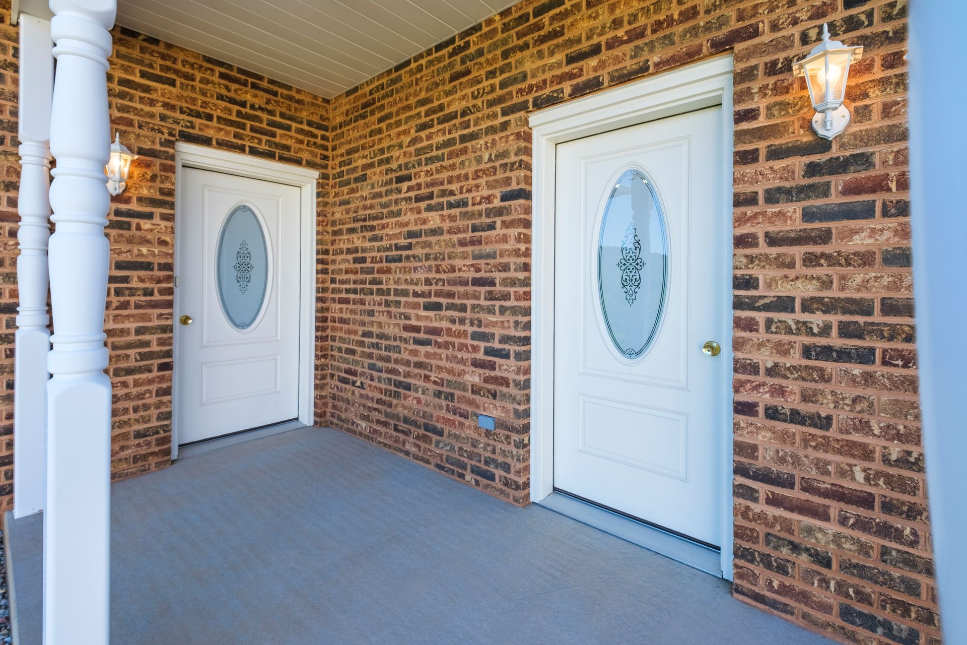 Brick apartment entryway with two white doors and a covered porch.