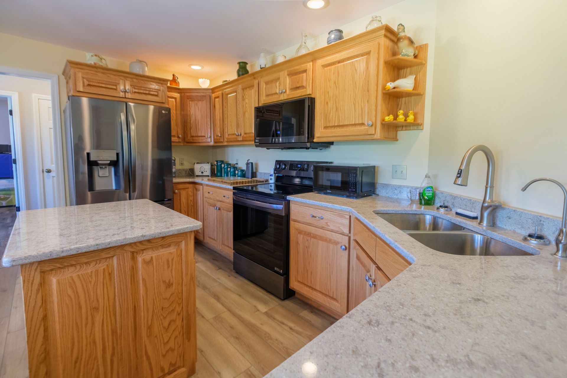Bright kitchen with oak cabinets, stainless steel appliances, granite counters, and a double sink
