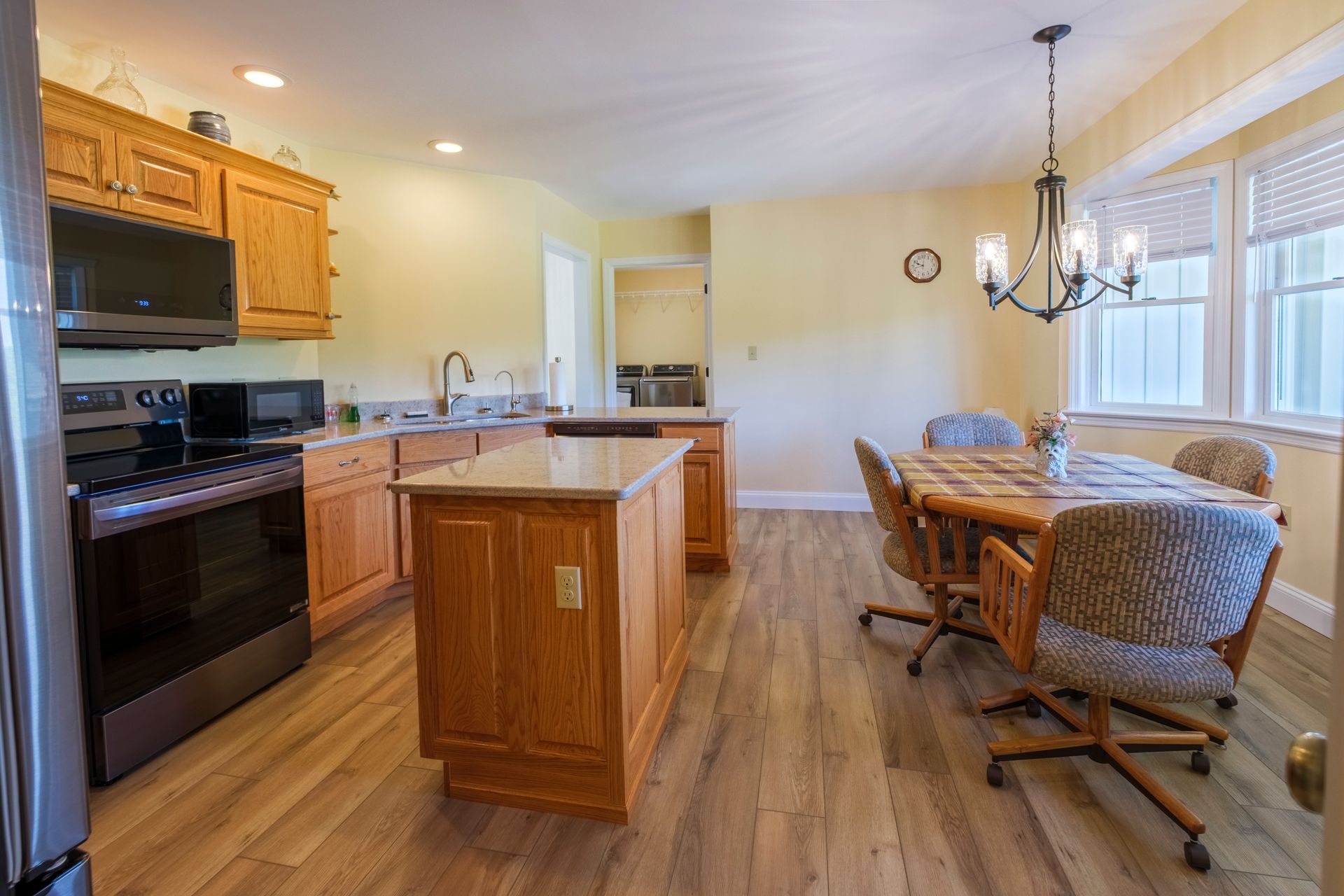 Bright kitchen and dining area with wood cabinets, island, black stove, and table by windows
