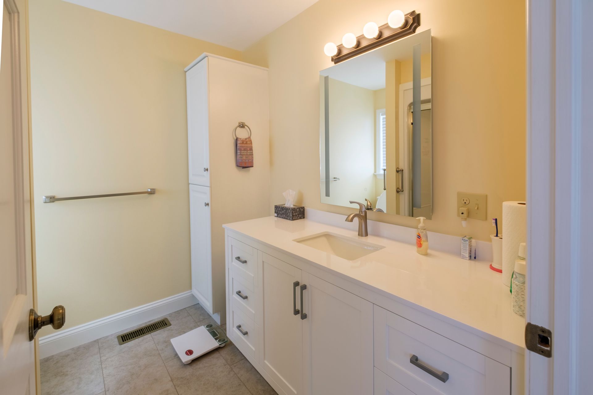 Bright bathroom with white vanity, large mirror, towel bar, and shower curtain in beige tones