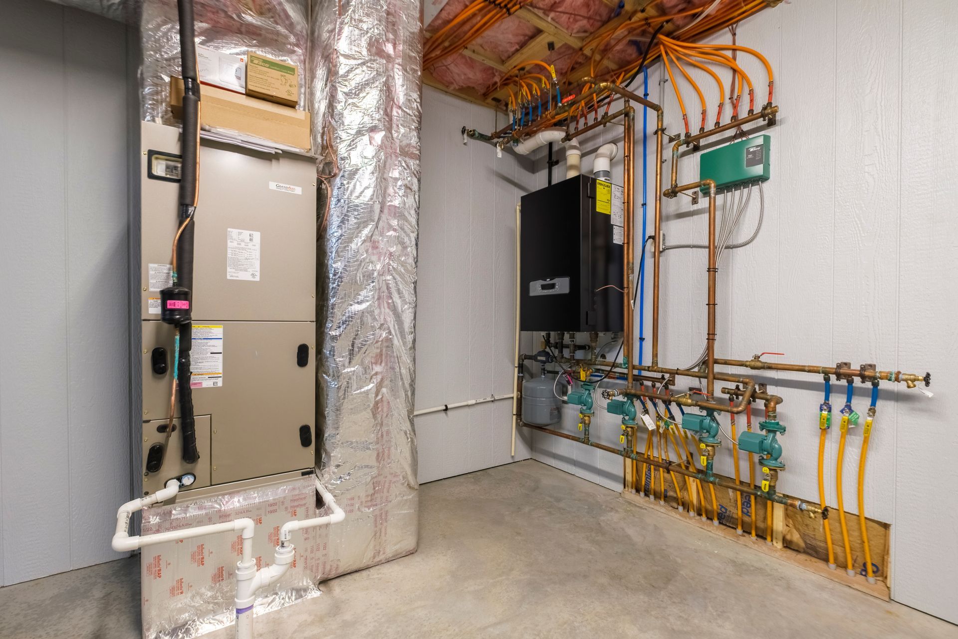 Mechanical room with HVAC units, insulated ducts, and orange electrical wiring along the wall.