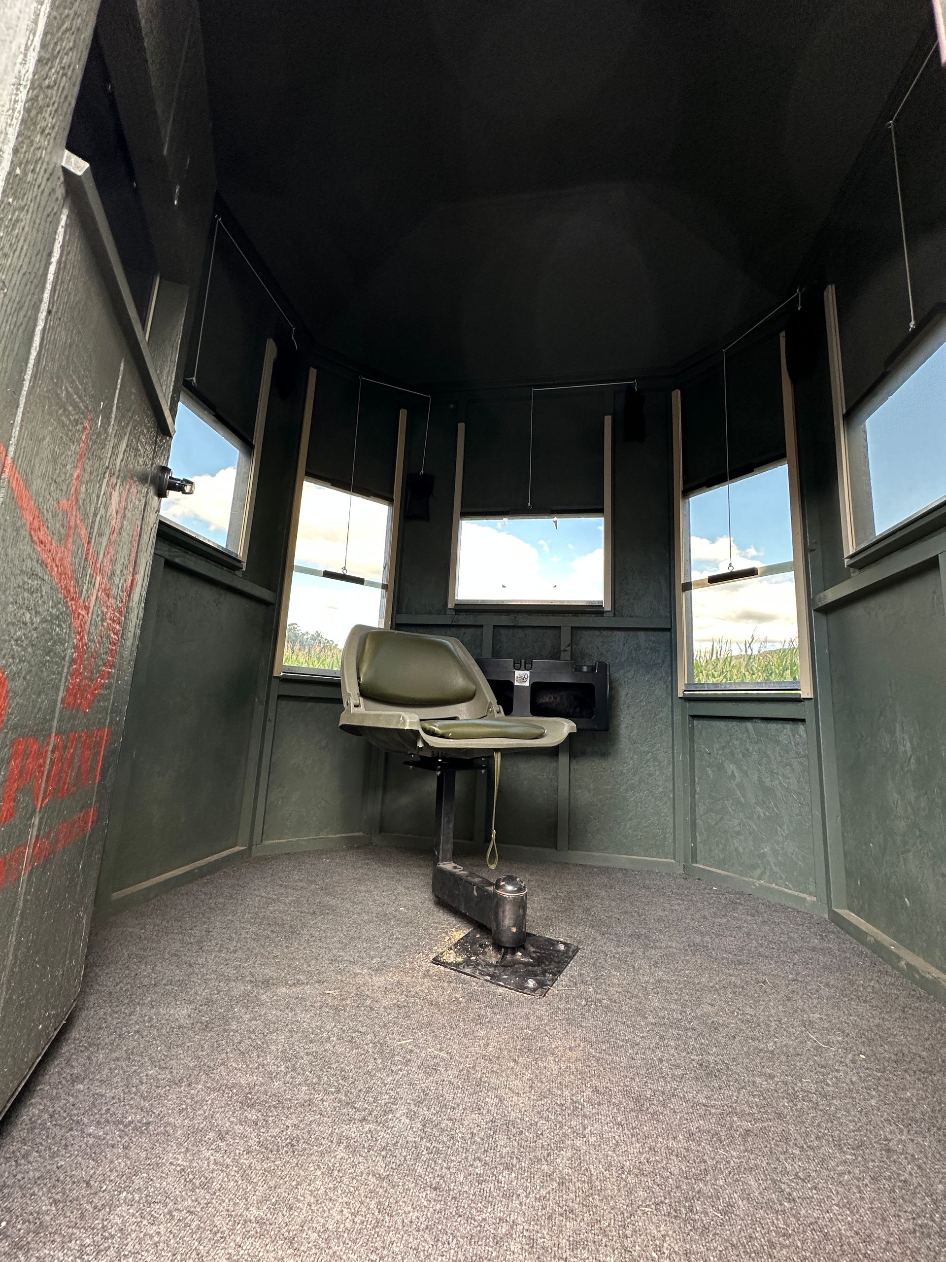 Small dark shelter interior with a single chair facing windows and a speckled floor