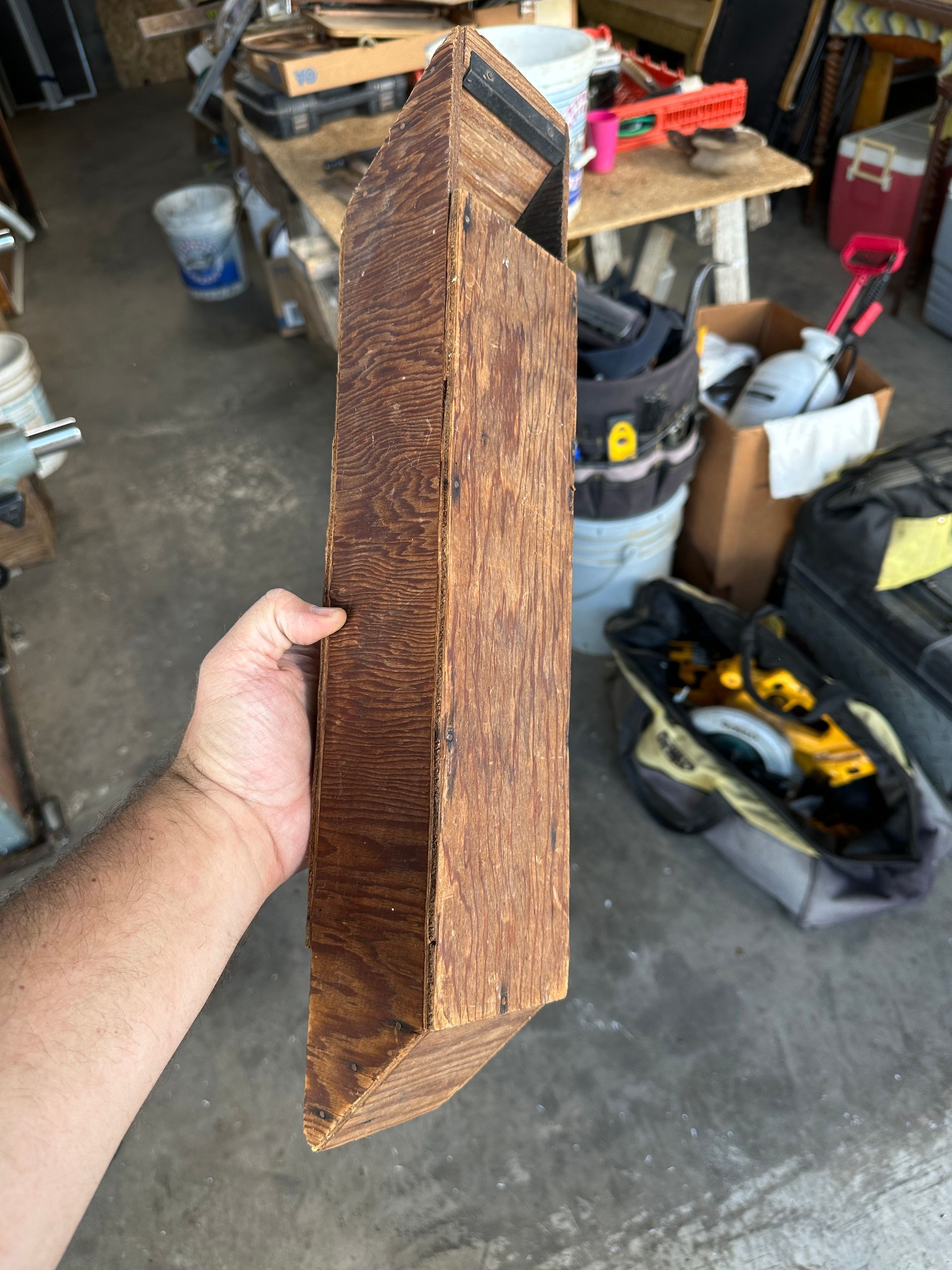 Hand holding a rusty triangular metal piece in a garage workshop