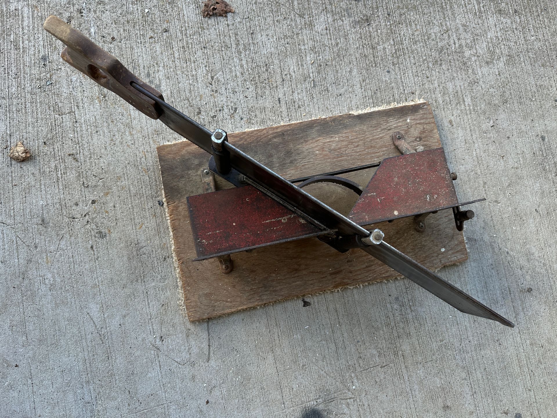 A small dark wooden model airplane mounted on a base, with weathered red wings and a propeller.