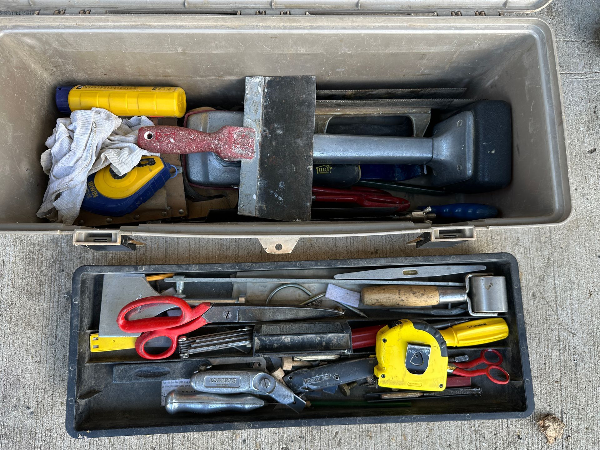 Open toolbox with assorted hand tools, including a yellow tape measure and red scissors