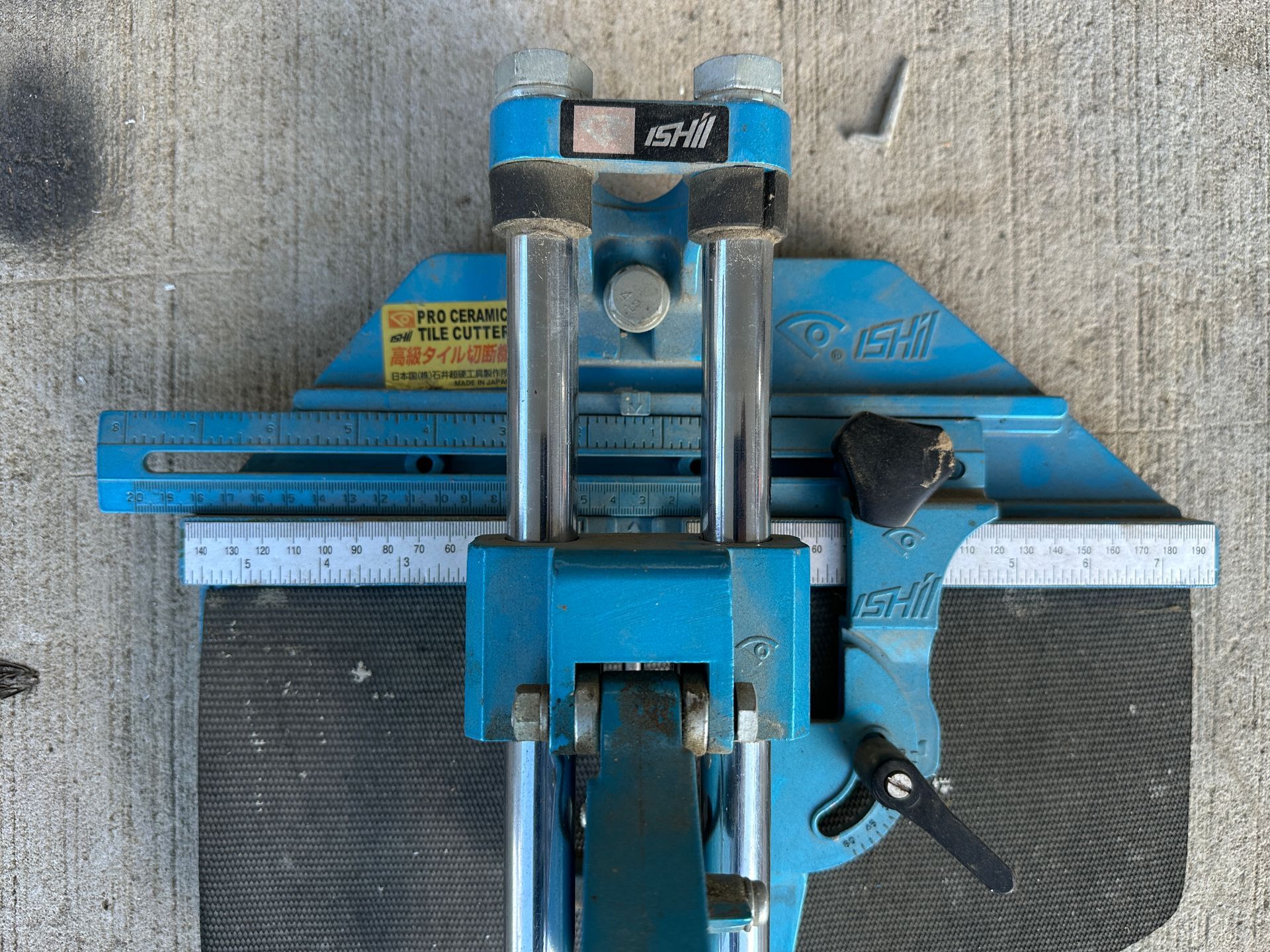 Blue metal machine on a gray surface, viewed from above.