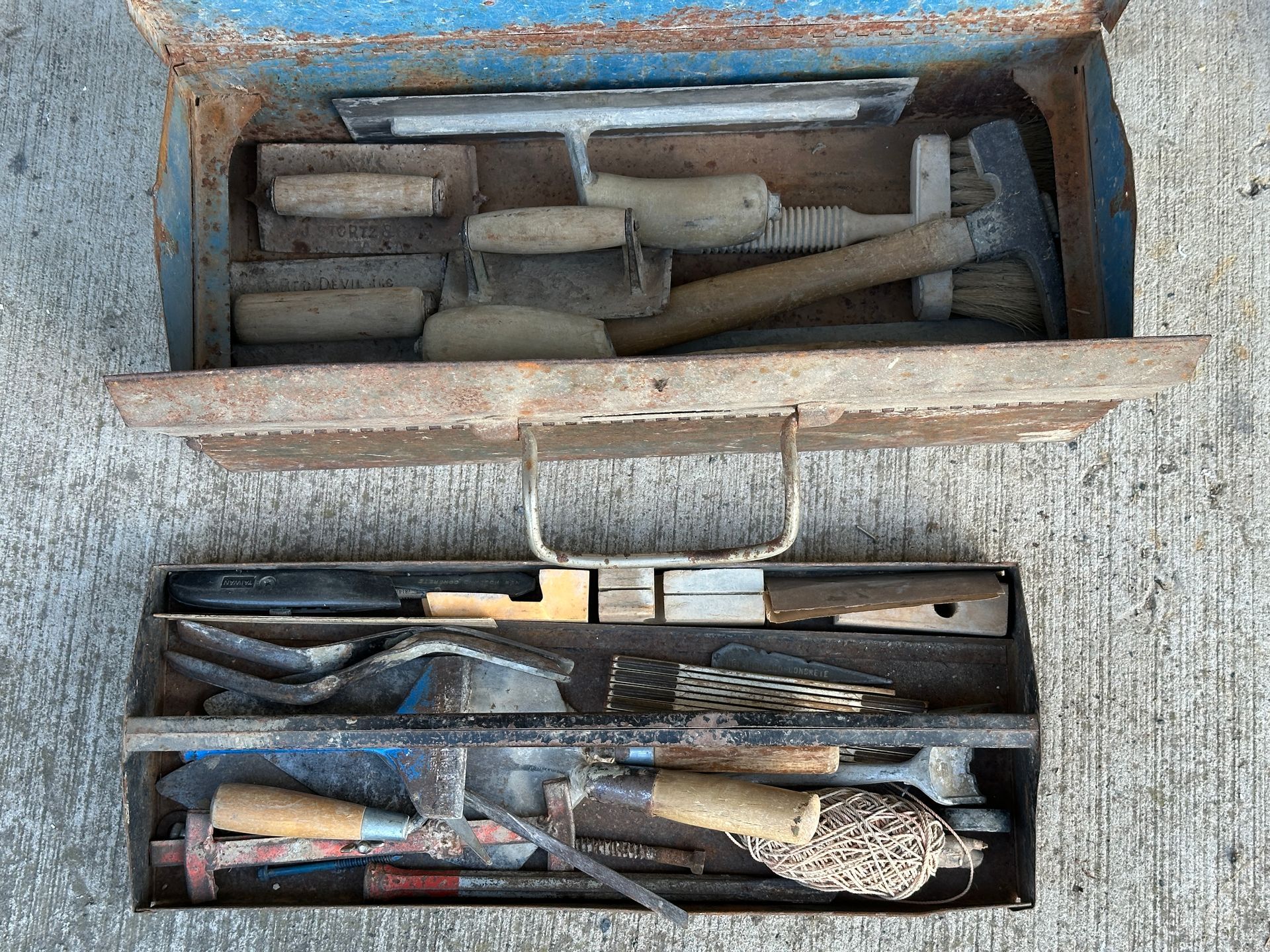 Open toolbox with assorted hand tools in a weathered blue case