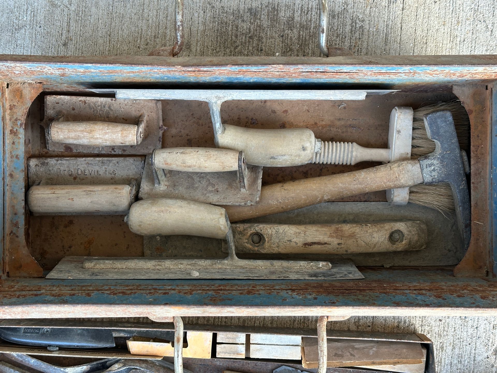 Wooden box filled with assorted old hand tools and chisels, viewed from above.