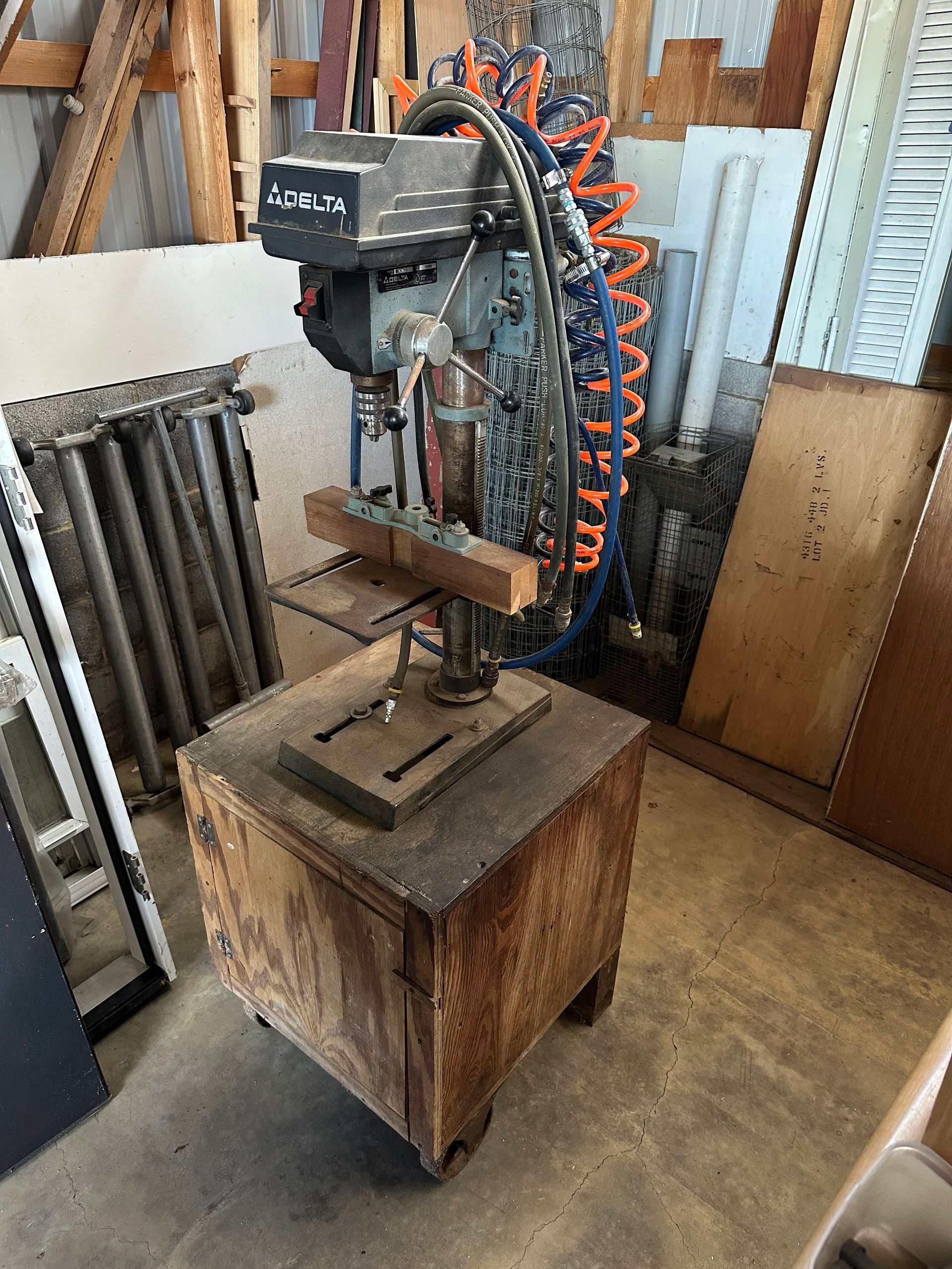 Large industrial machine with orange hoses mounted on a wooden crate in a workshop