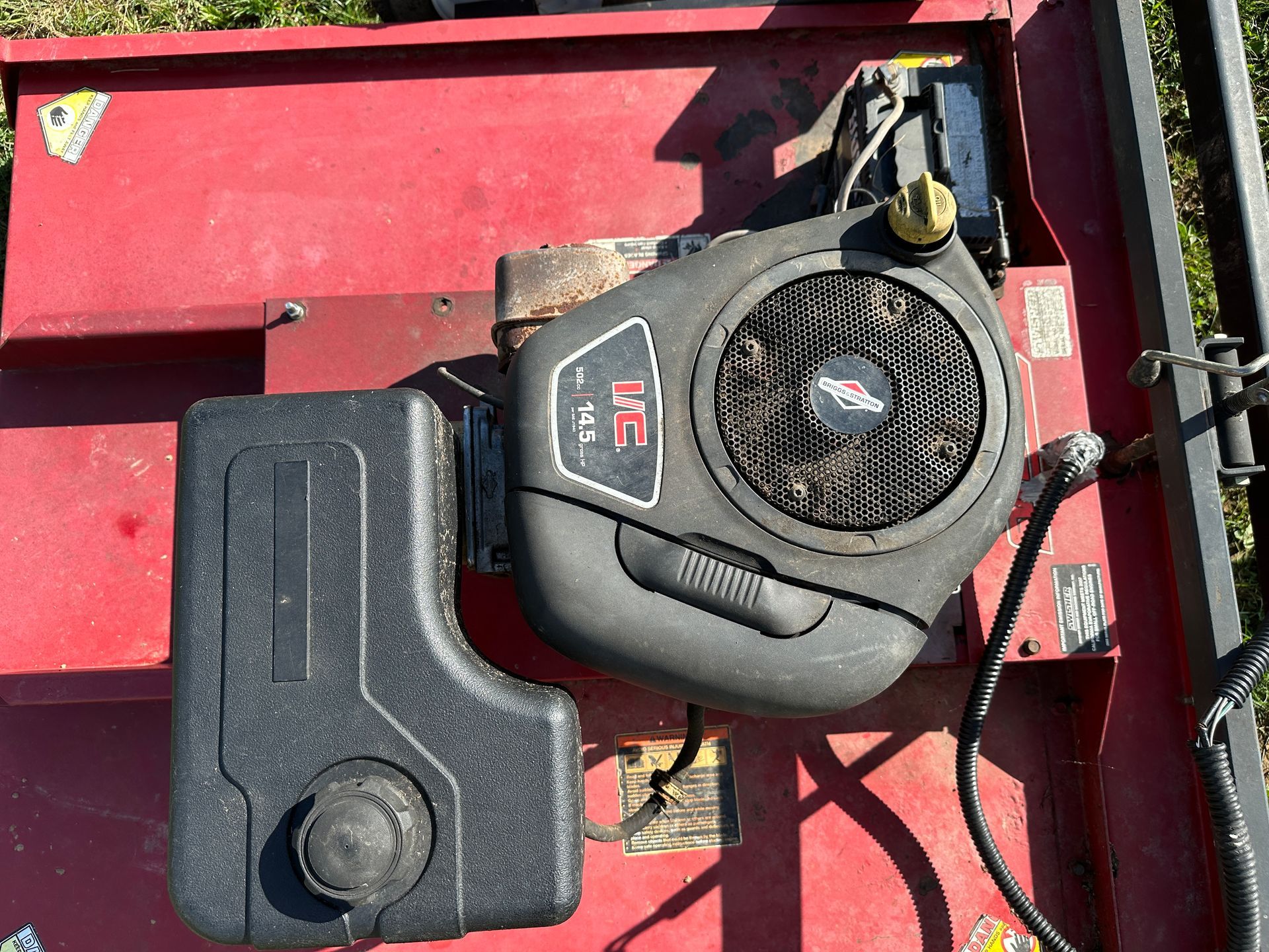 Two small engines on a red surface, one black and one gray, viewed from above.