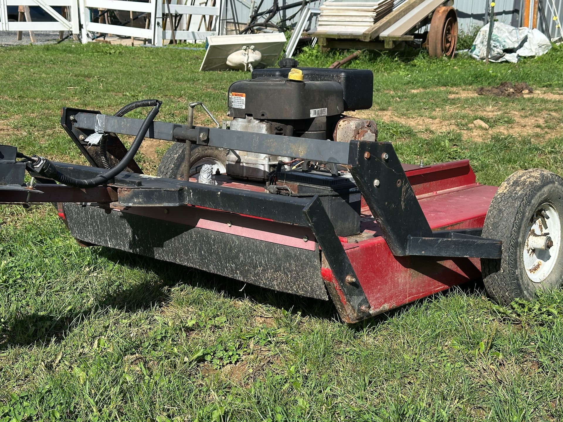 Red and black riding lawn mower parked on grass in a yard