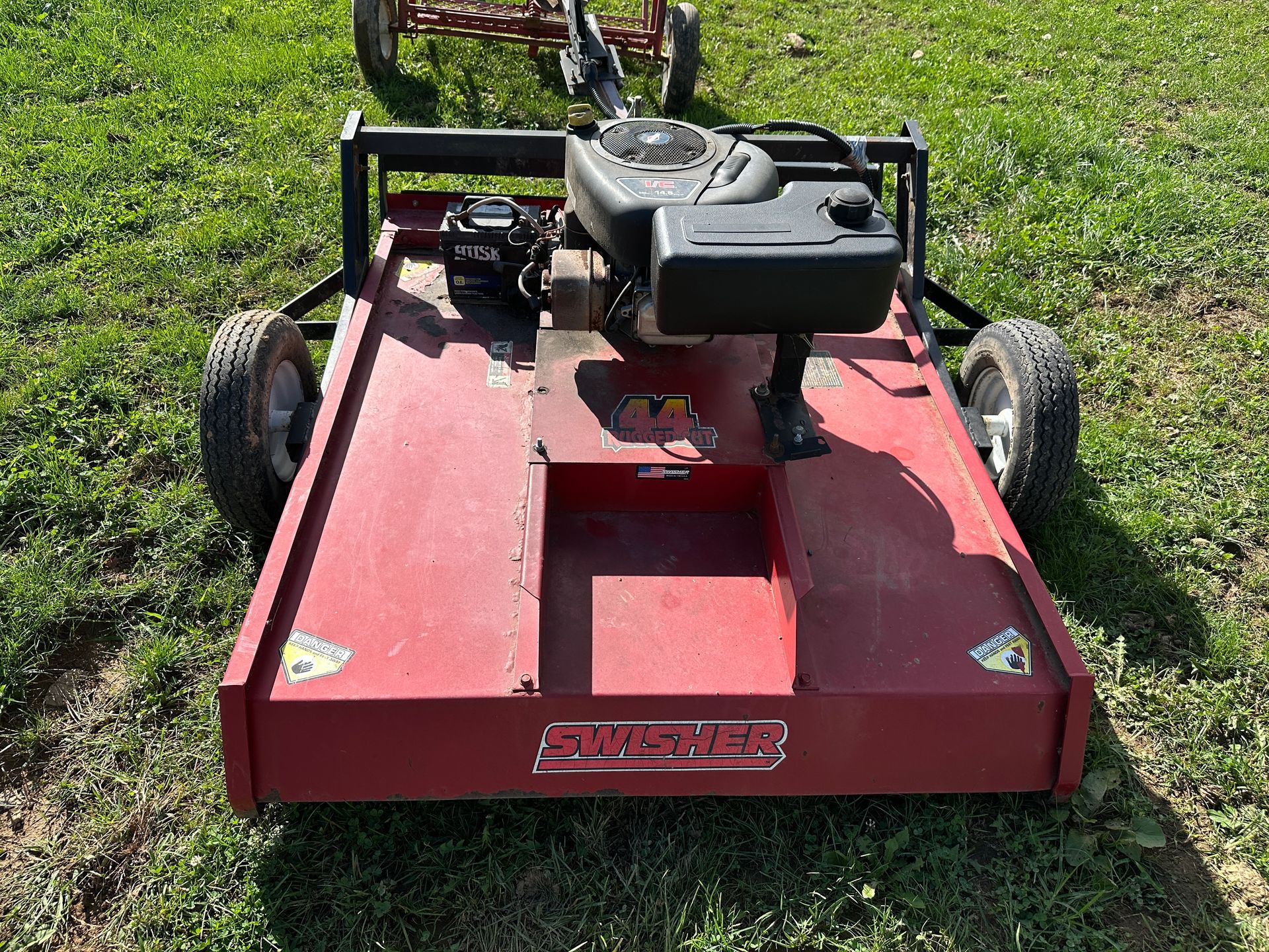 Red riding lawn mower on grass, viewed from the front