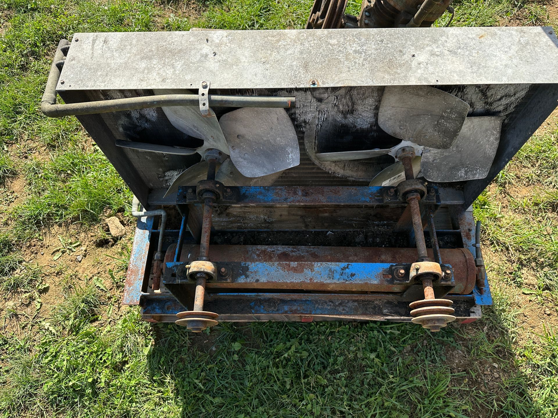 Open metal utility box with pipes and valves in grass, viewed from above
