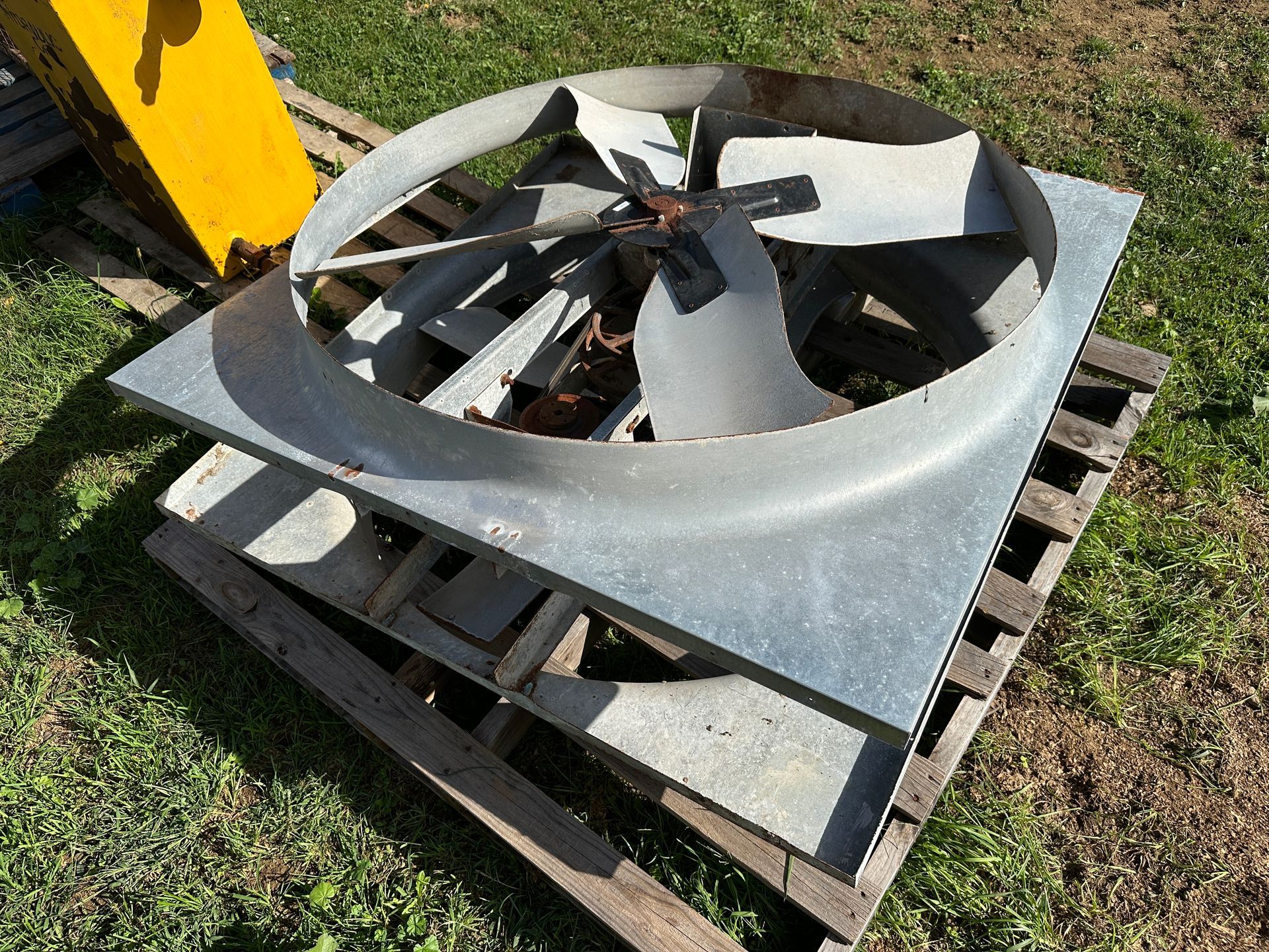 Large metal industrial fan blade assembly on a wooden pallet outdoors on grass