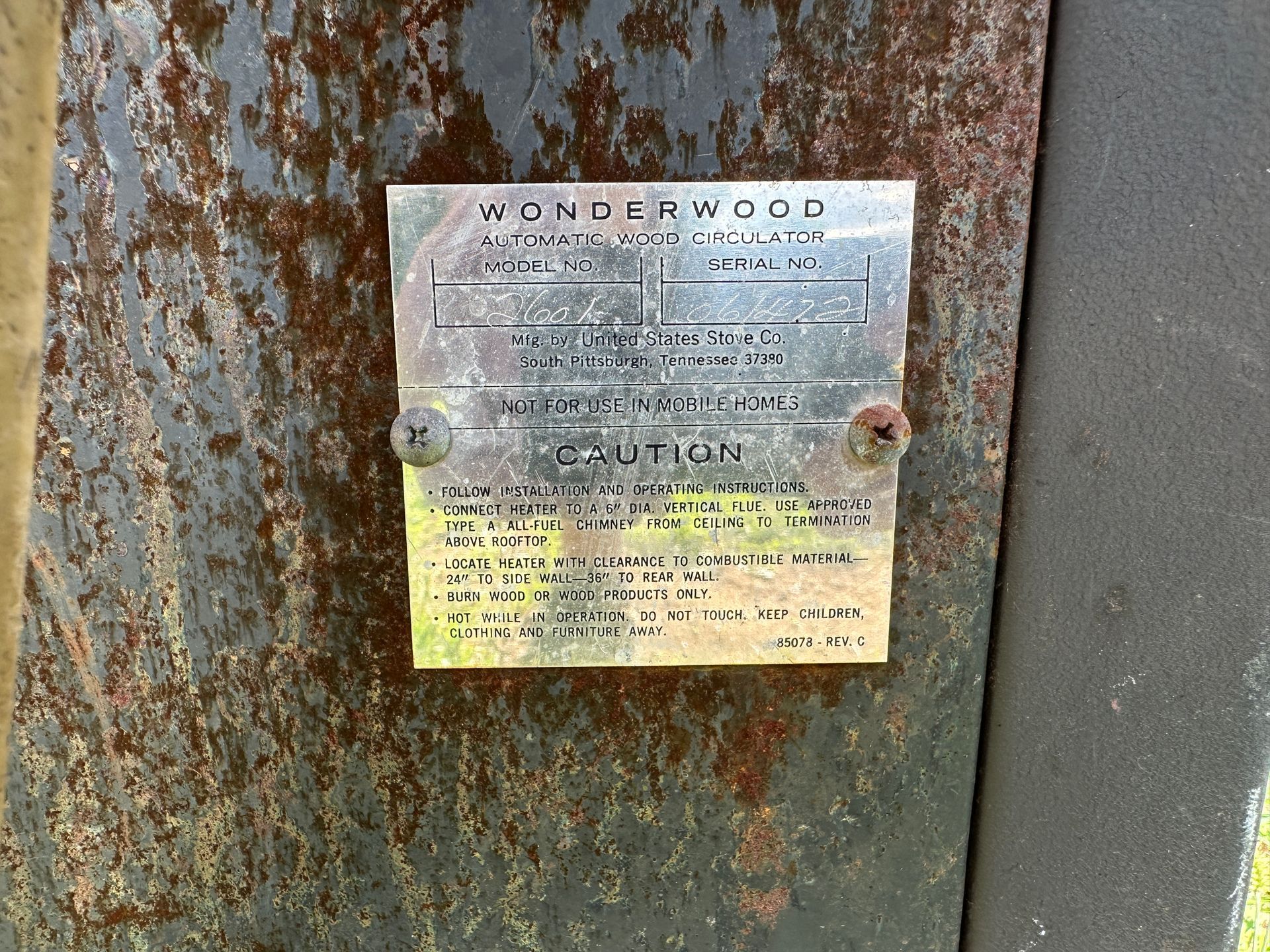 Weathered metal plaque on a rusty door, with faded text and a silver top fading to yellow at the bottom