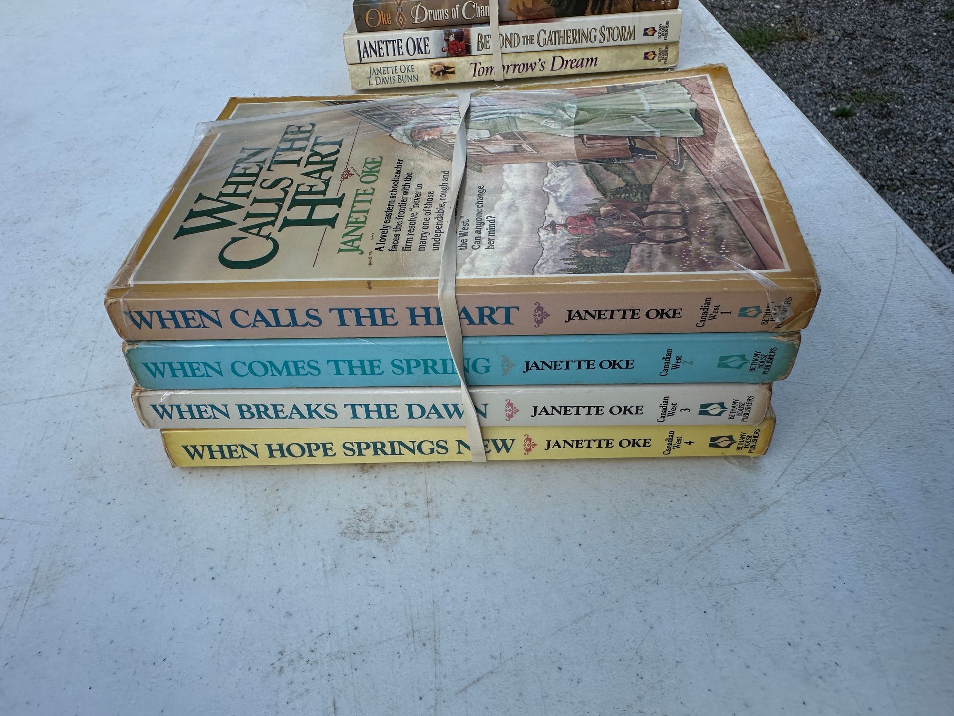 Stack of colorful vintage paperback books on a light blue surface, with one book on top.