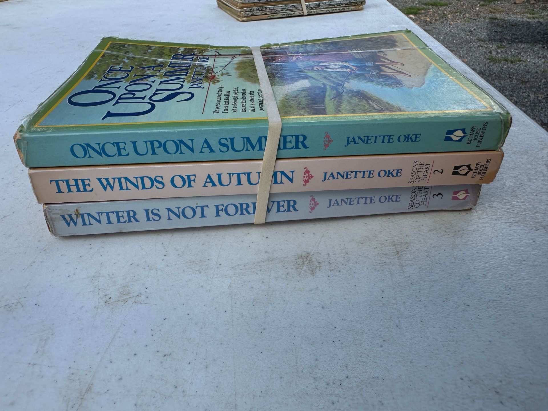 Three stacked colorful books on a concrete surface outdoors
