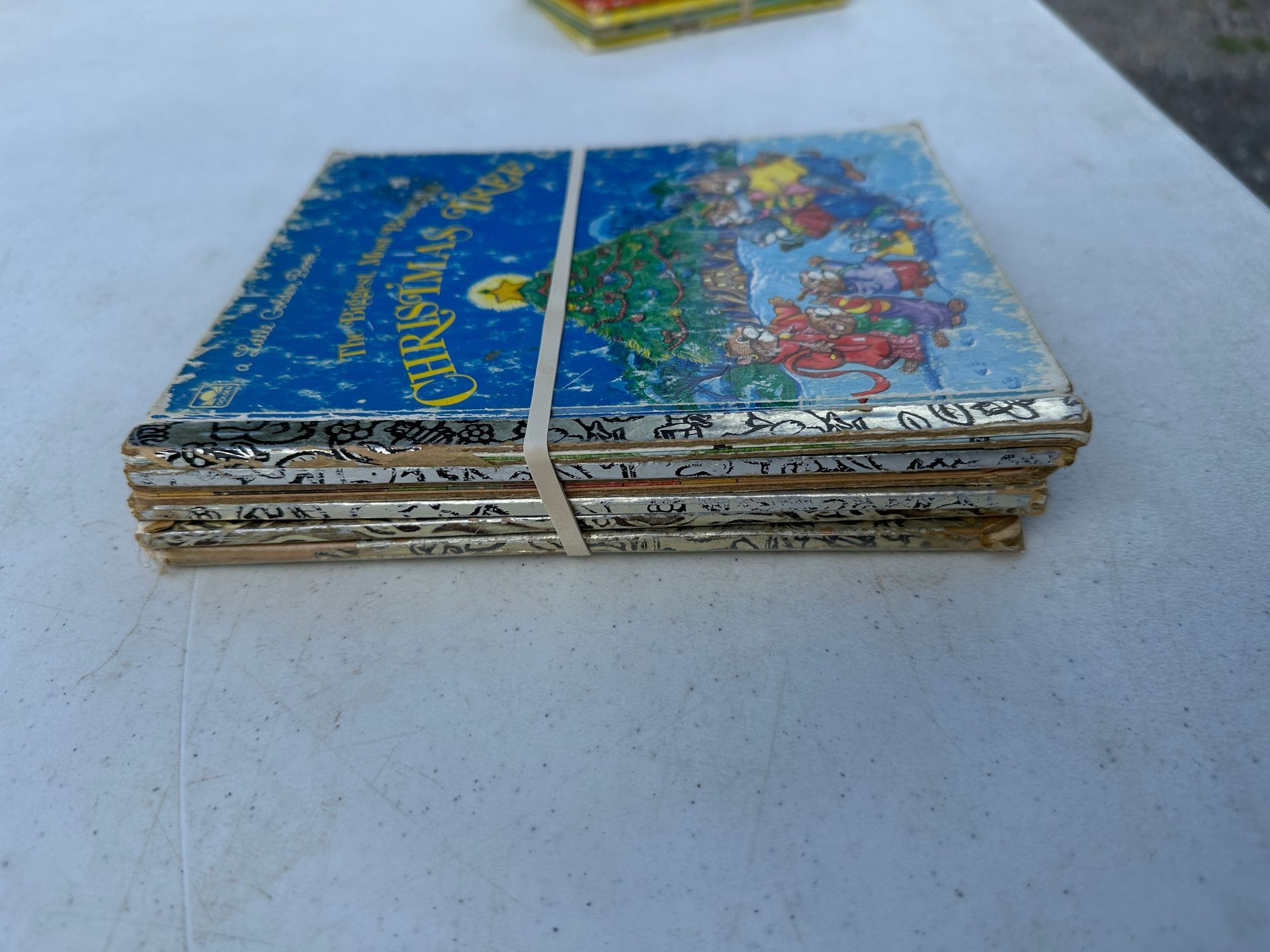 Stack of colorful notebooks with a white strap on a light table.