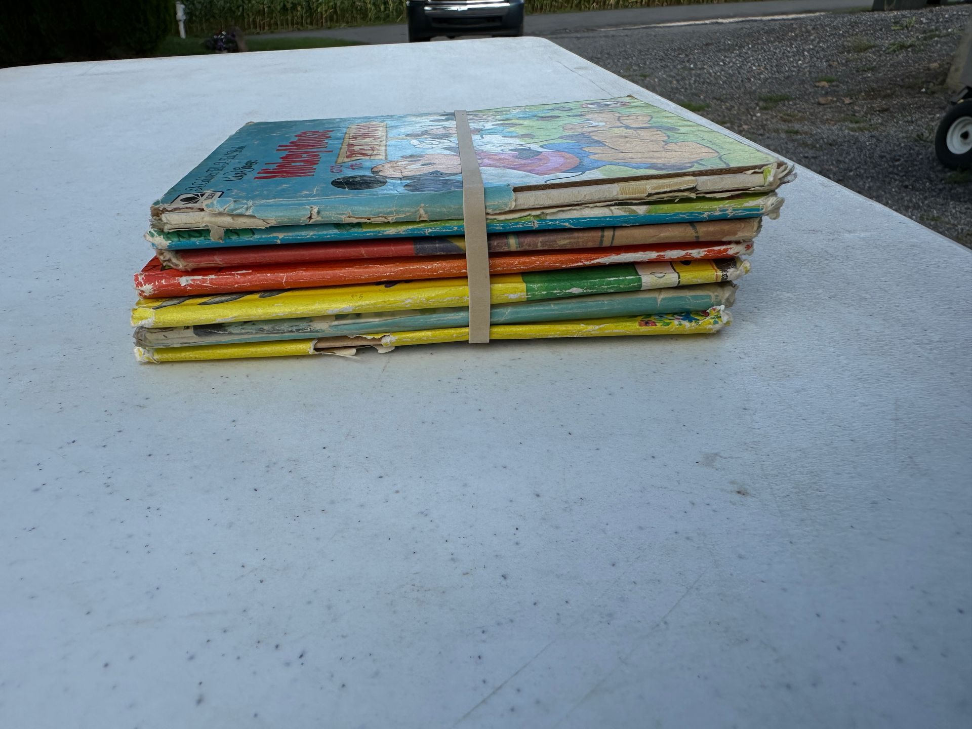 Stack of colorful books on a white tabletop outdoors