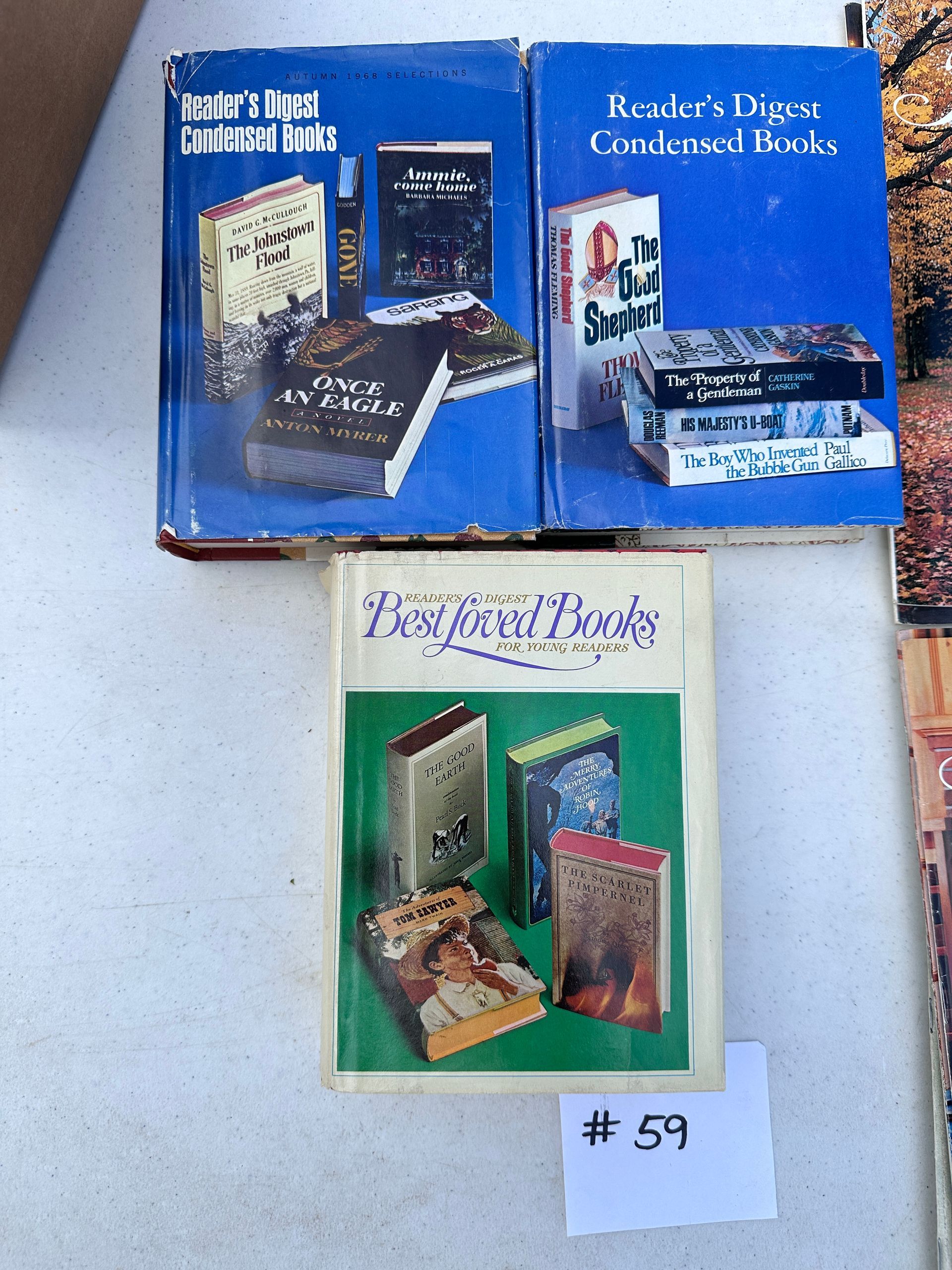 Three boxed book sets on a light blue surface, with a small handwritten “#59” label below