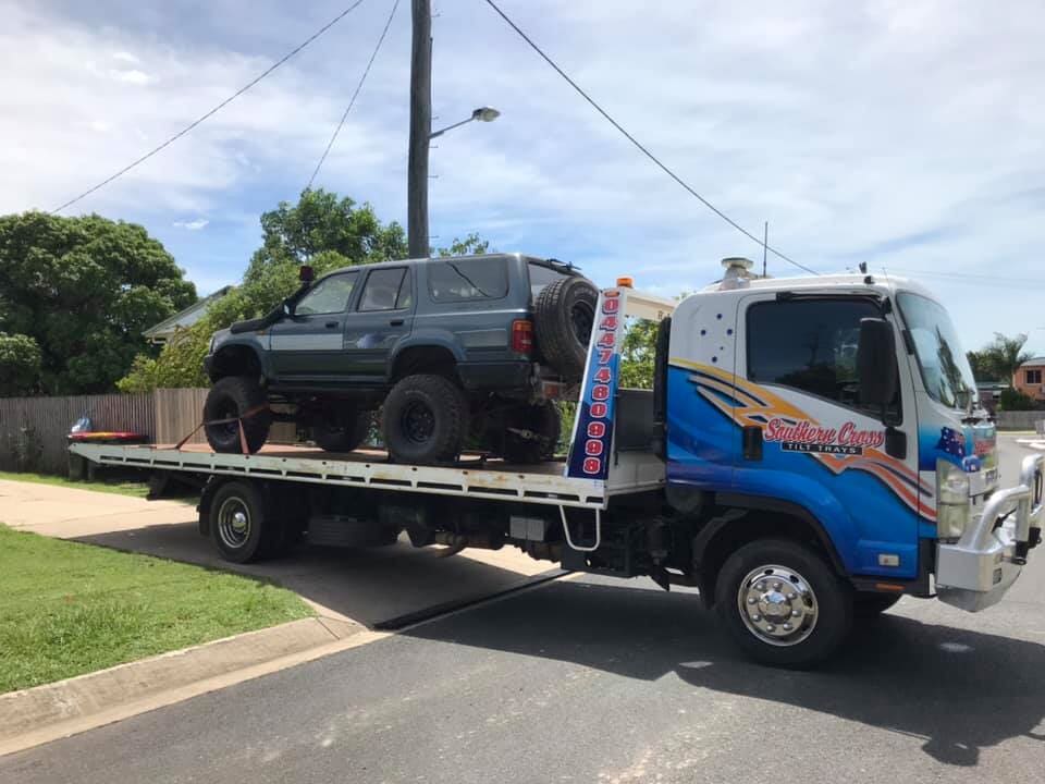 A White Car is Being Towed by a Tow Truck on a Highway — Southern Cross Tilt Trays in Peak Downs, QLD