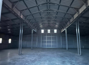 Empty metal warehouse interior with corrugated roof and concrete floor
