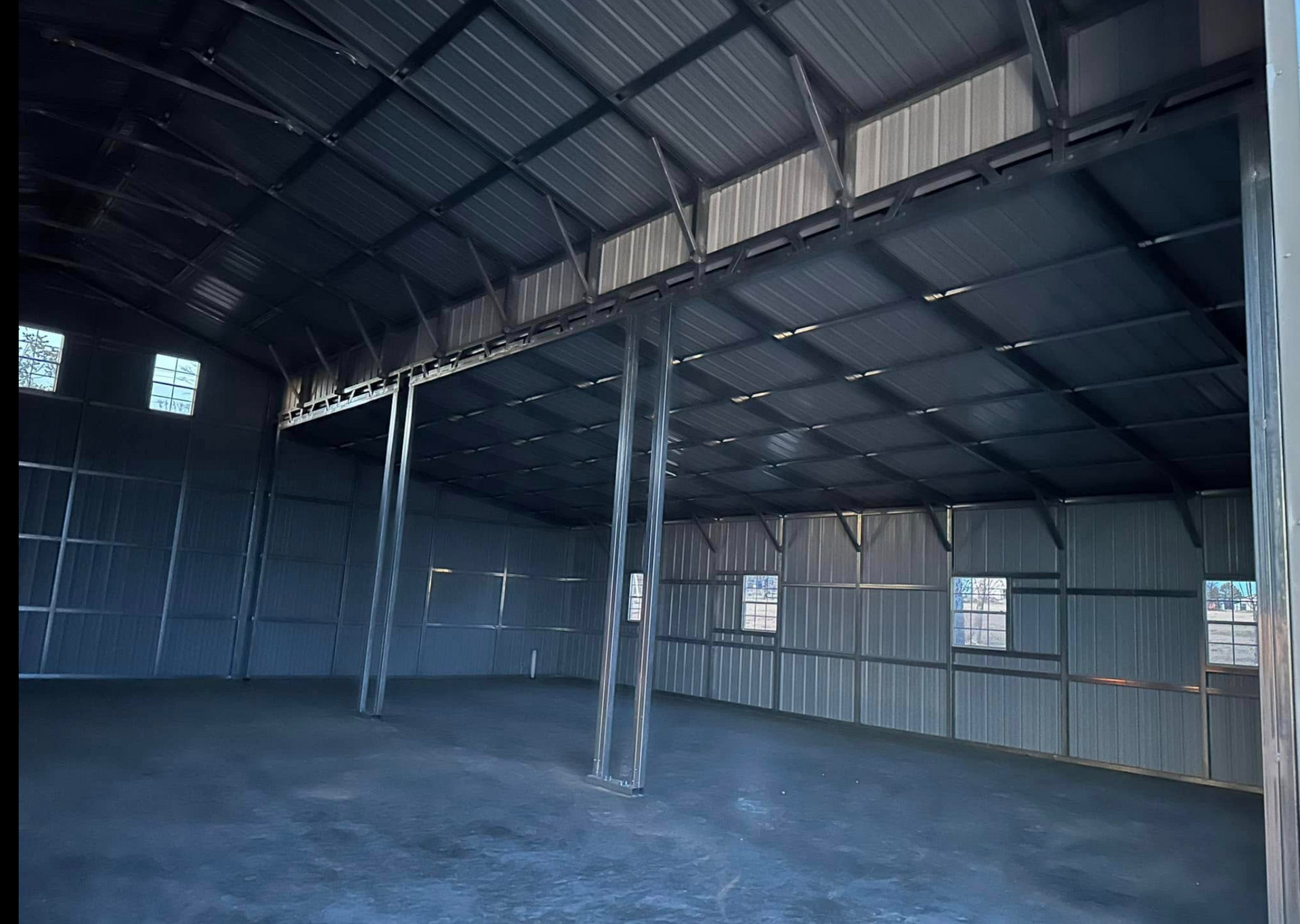 Empty metal warehouse interior with corrugated walls, steel beams, and a concrete floor