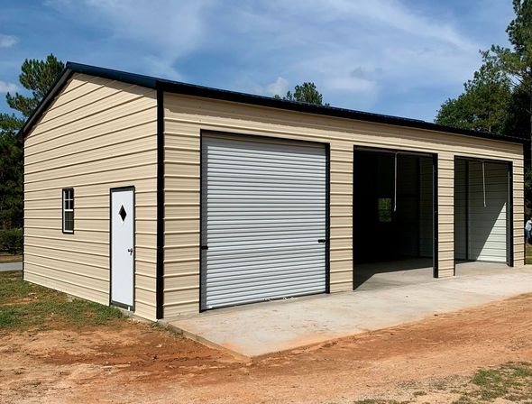 Beige metal garage building with roll-up door and open bays on a dirt lot