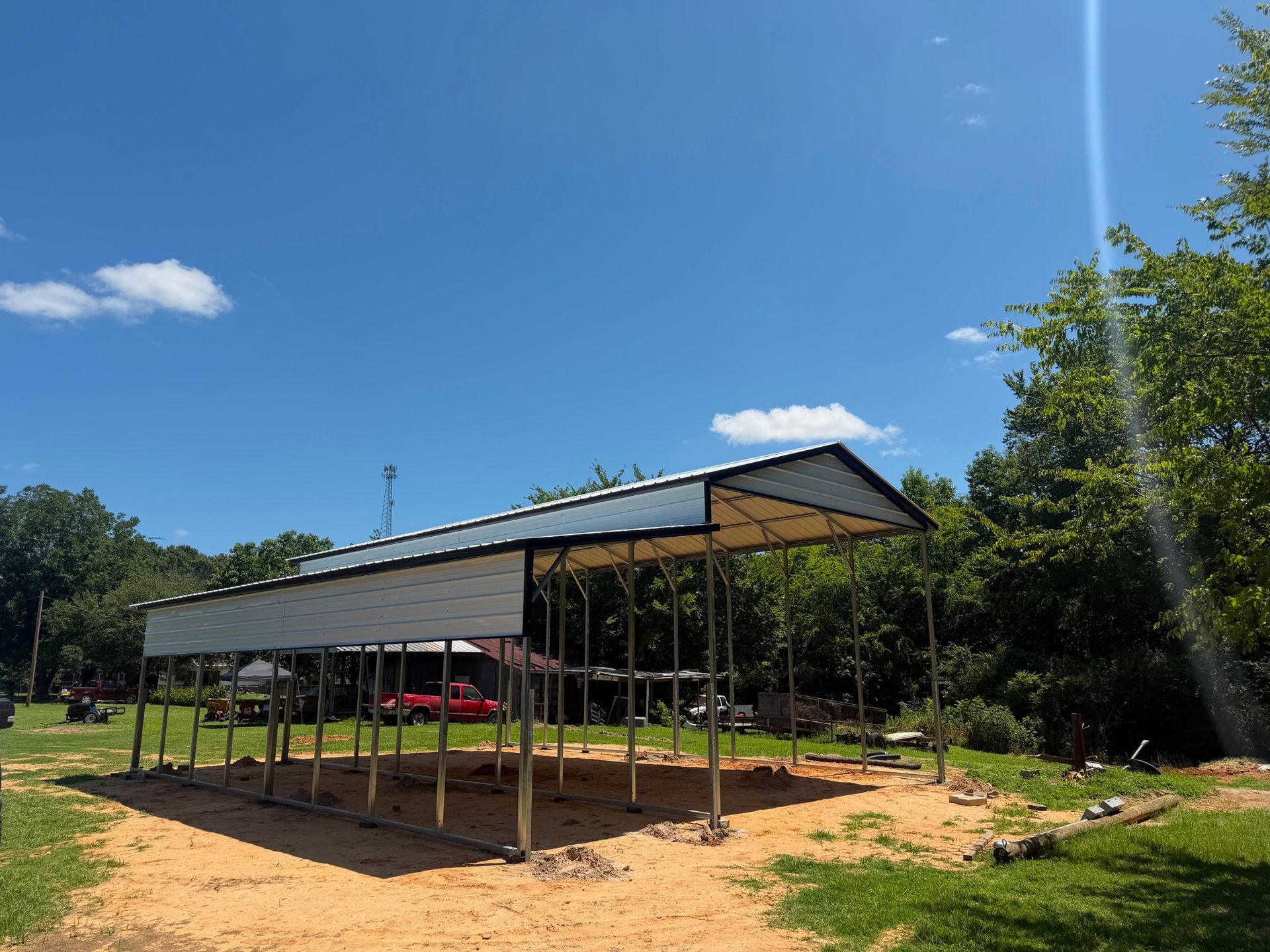 Red metal utility building with two gray roll-up garage doors under a blue sky