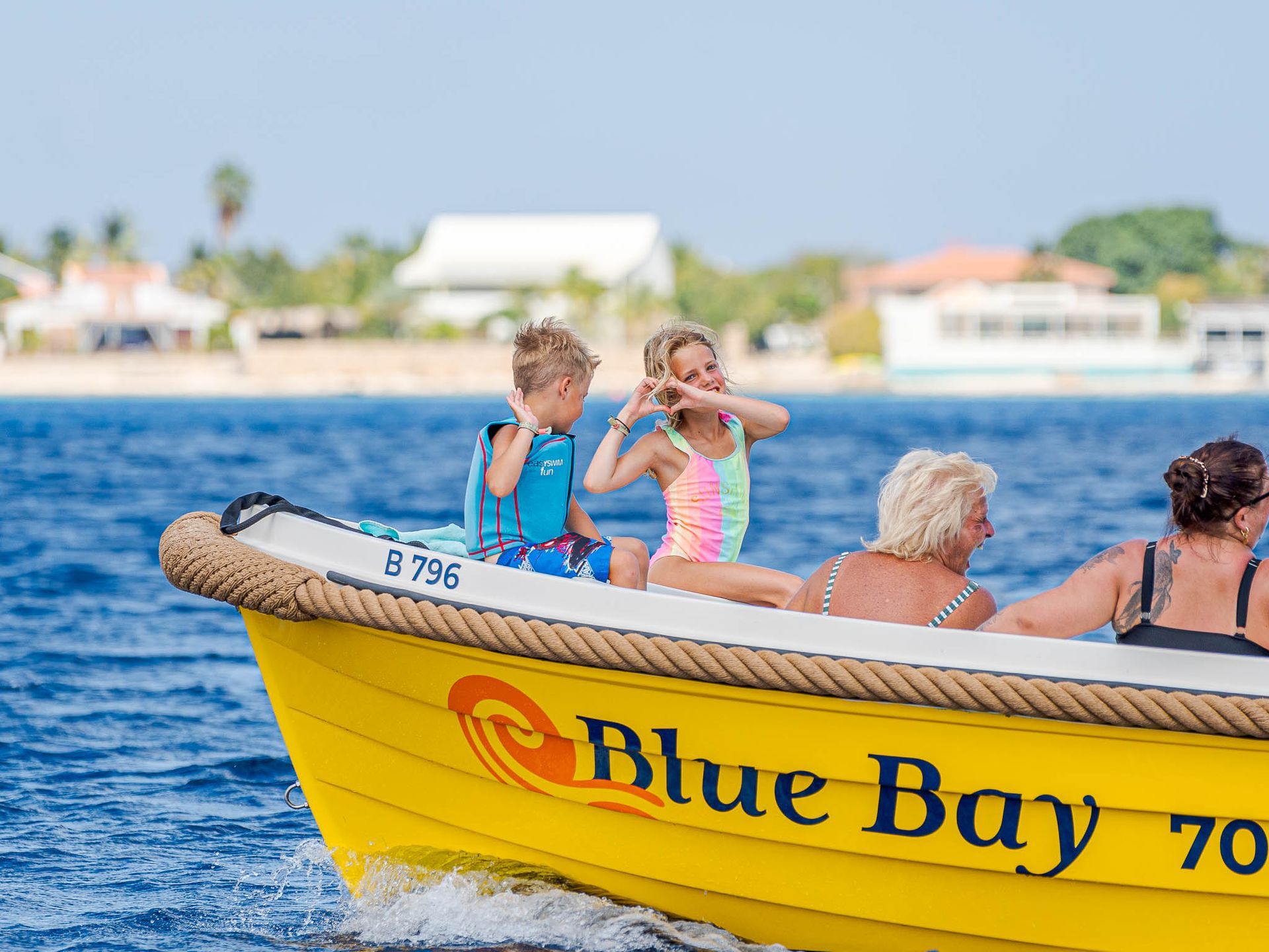 Blue Bay Gele sloep met 2 kinderen voorop die een hartje maken naar de camera | varen zonder vaarbewijs.