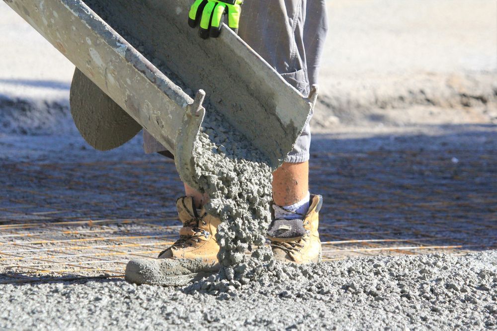 A person is pouring concrete into the ground with a shovel.
