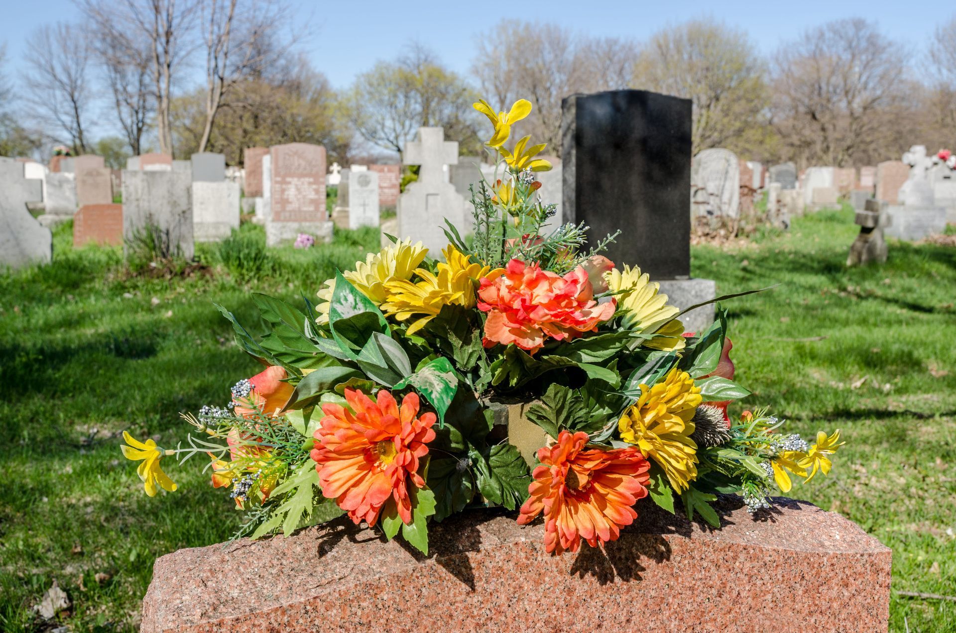 Gravesite with colorful flower arrangement on a headstone in a cemetery
