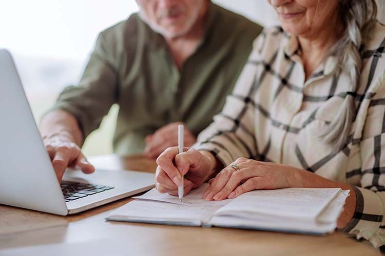 Two people reviewing documents at a table beside a laptop