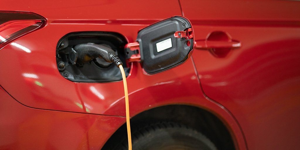A close up of a red electric car being charged.
