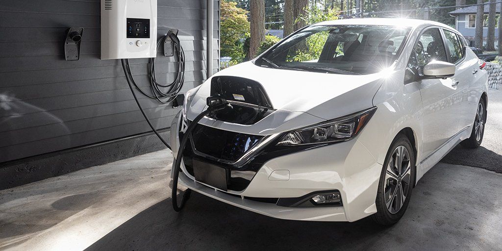 A white electric car is being charged at a home charging station.