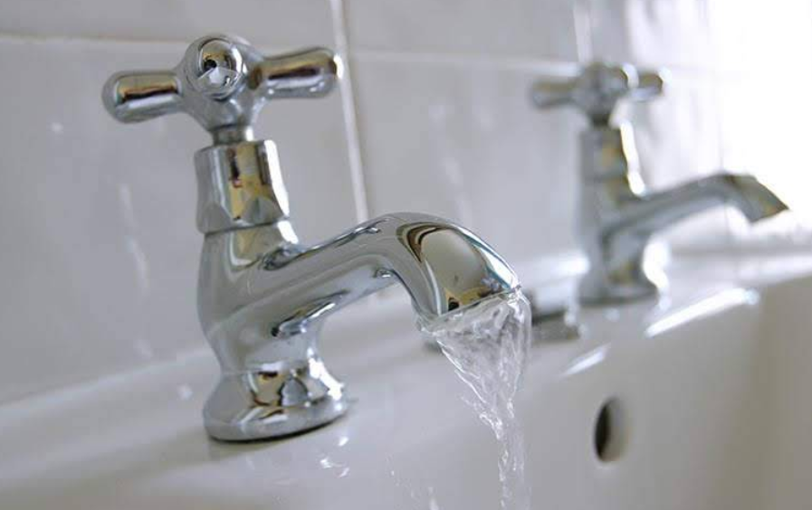 Chrome bathroom faucets with water running into a sink.