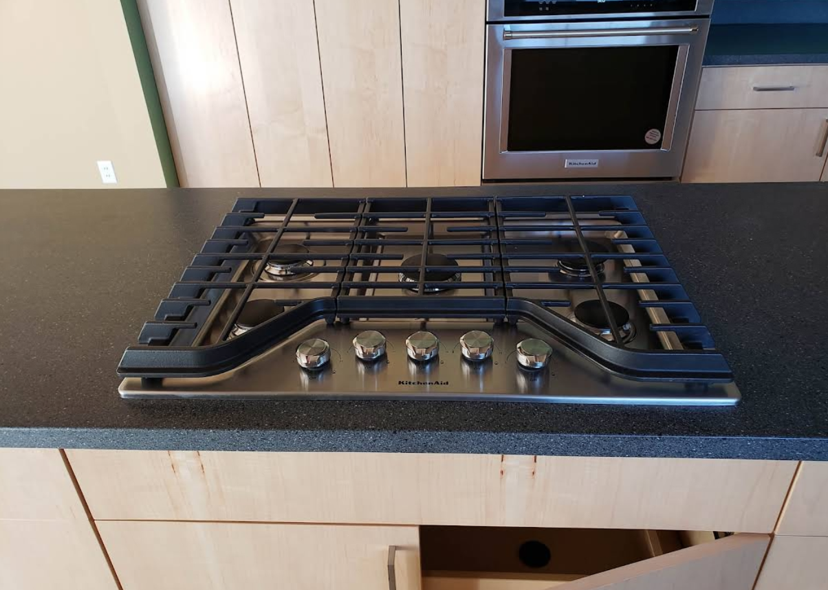 Kitchen countertop with a built-in gas cooktop and oven, viewed from the front.