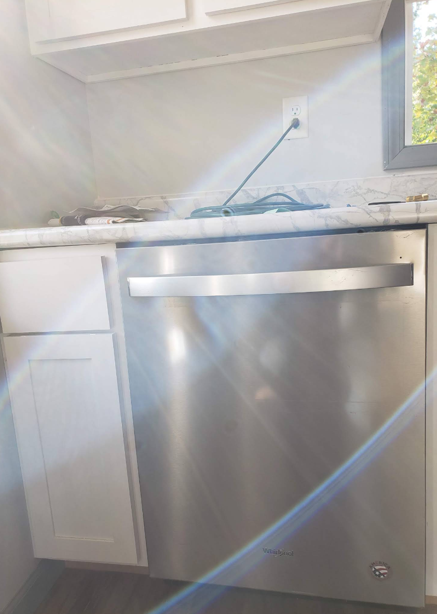 Small kitchen with a stainless steel dishwasher under a counter and a white cabinet beside it.