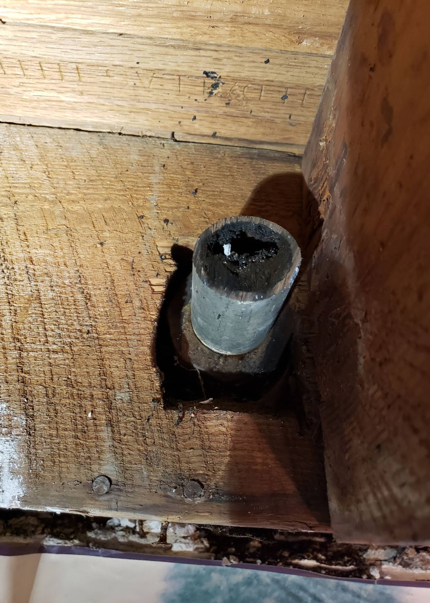 Close-up of a metal bolt or fastener set into a worn wooden surface.