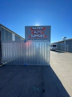 Napier Auto Supplies sign above metal fence on a sunny industrial lot