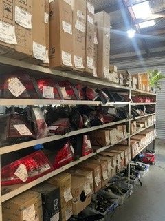 Shelves of boxed packages and red product bags in a warehouse aisle