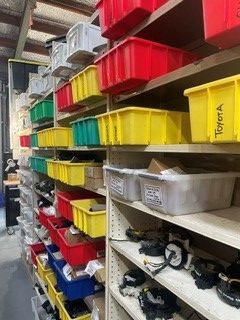 Warehouse shelves lined with colorful plastic storage bins and assorted parts