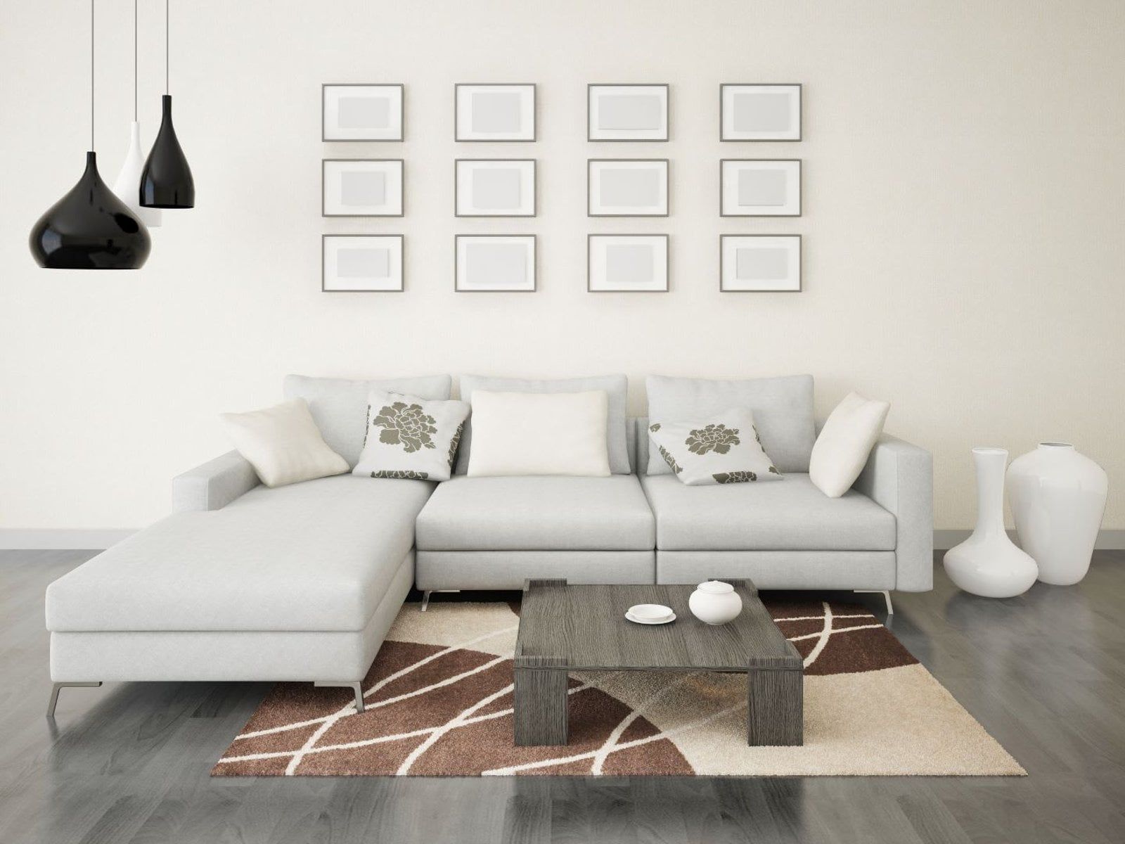 Living room with a gray sectional sofa, coffee table, rug, and pendant lights. Blank picture frames on the wall.