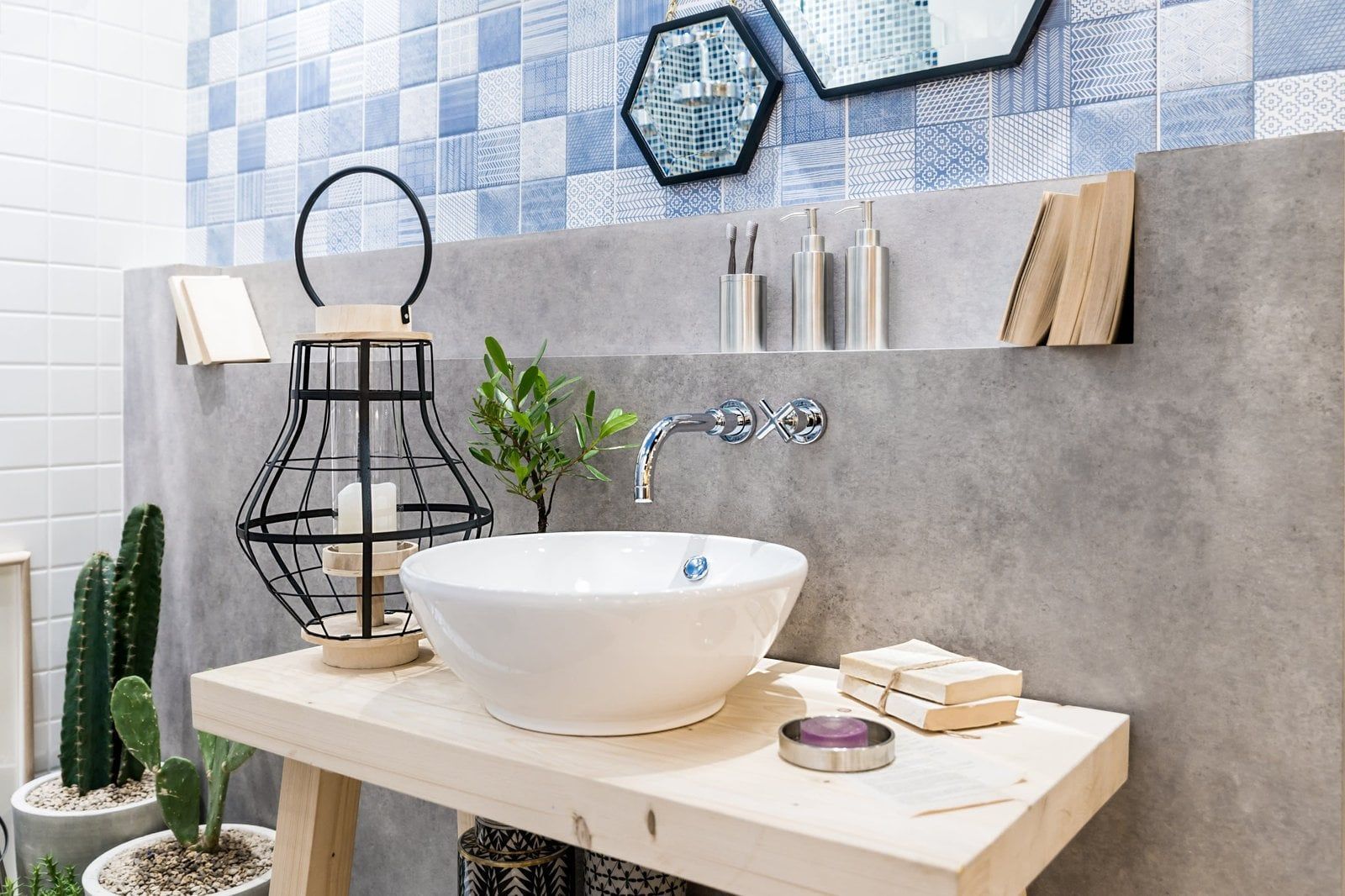 Bathroom with a white sink on a wooden table, blue tiled wall, and decorative lantern and plants.