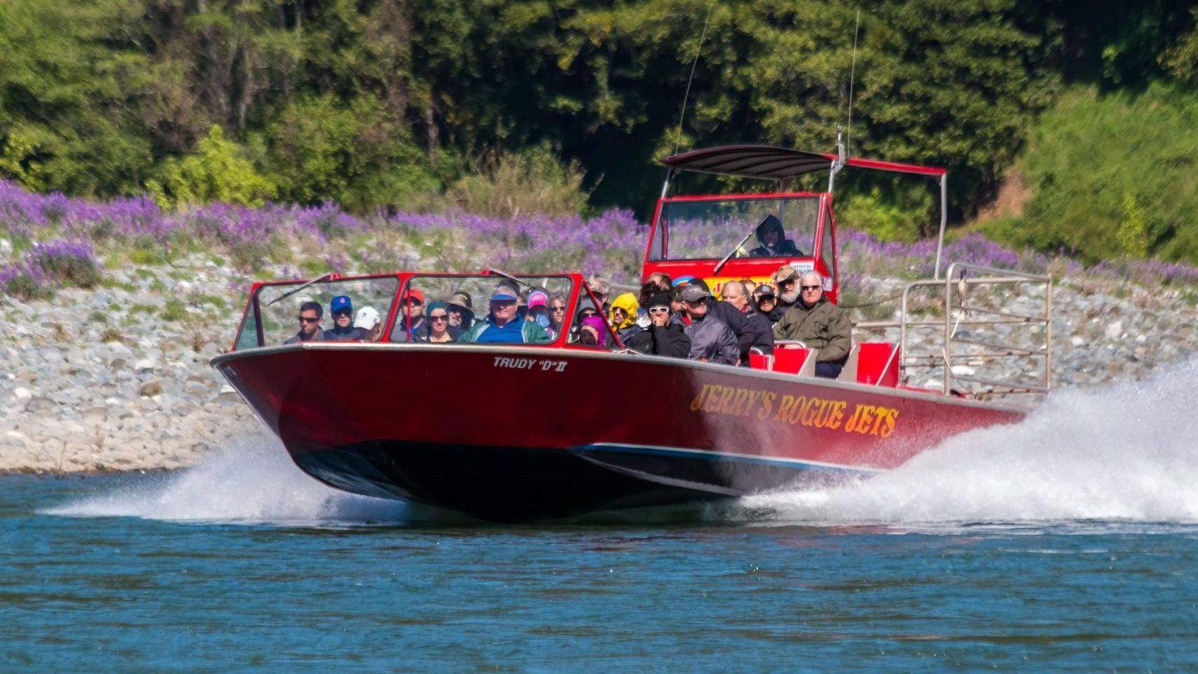 a group of people are riding a red boat down a river through the rapids