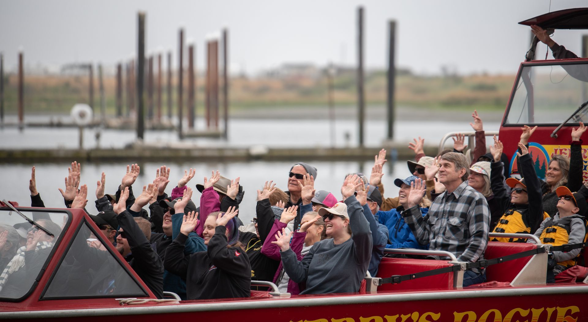 a group of people sitting on a red boat with their hands in the air