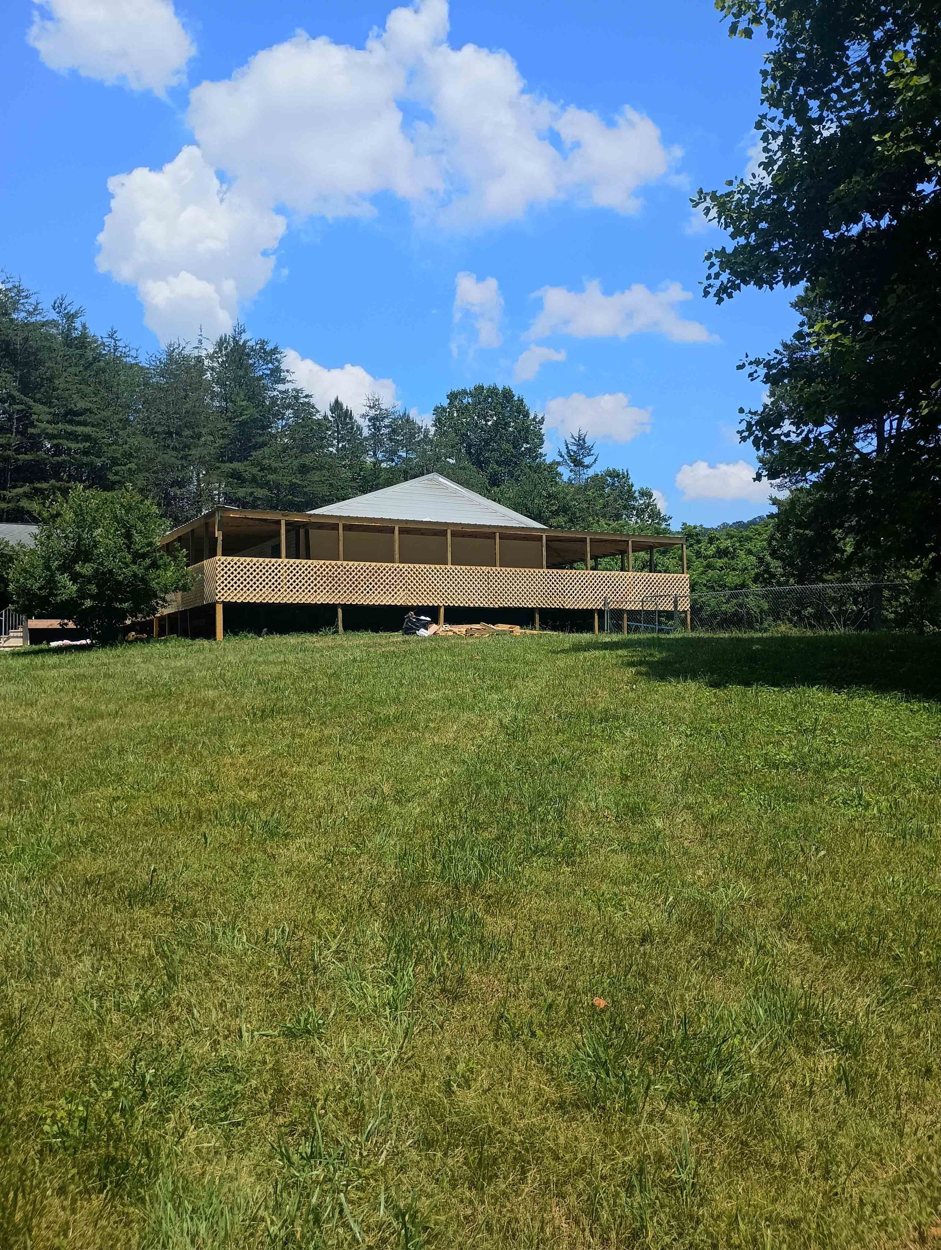 House With A Deck Is Sitting On Top Of A Lush Green Field — Knoxville, TN — DABZ CO LLC Electrical & Building Contractors House With A Deck Is Sitting On Top Of A Lush Green Field — Knoxville, TN — DABZ CO LLC Electrical & Building Contractors