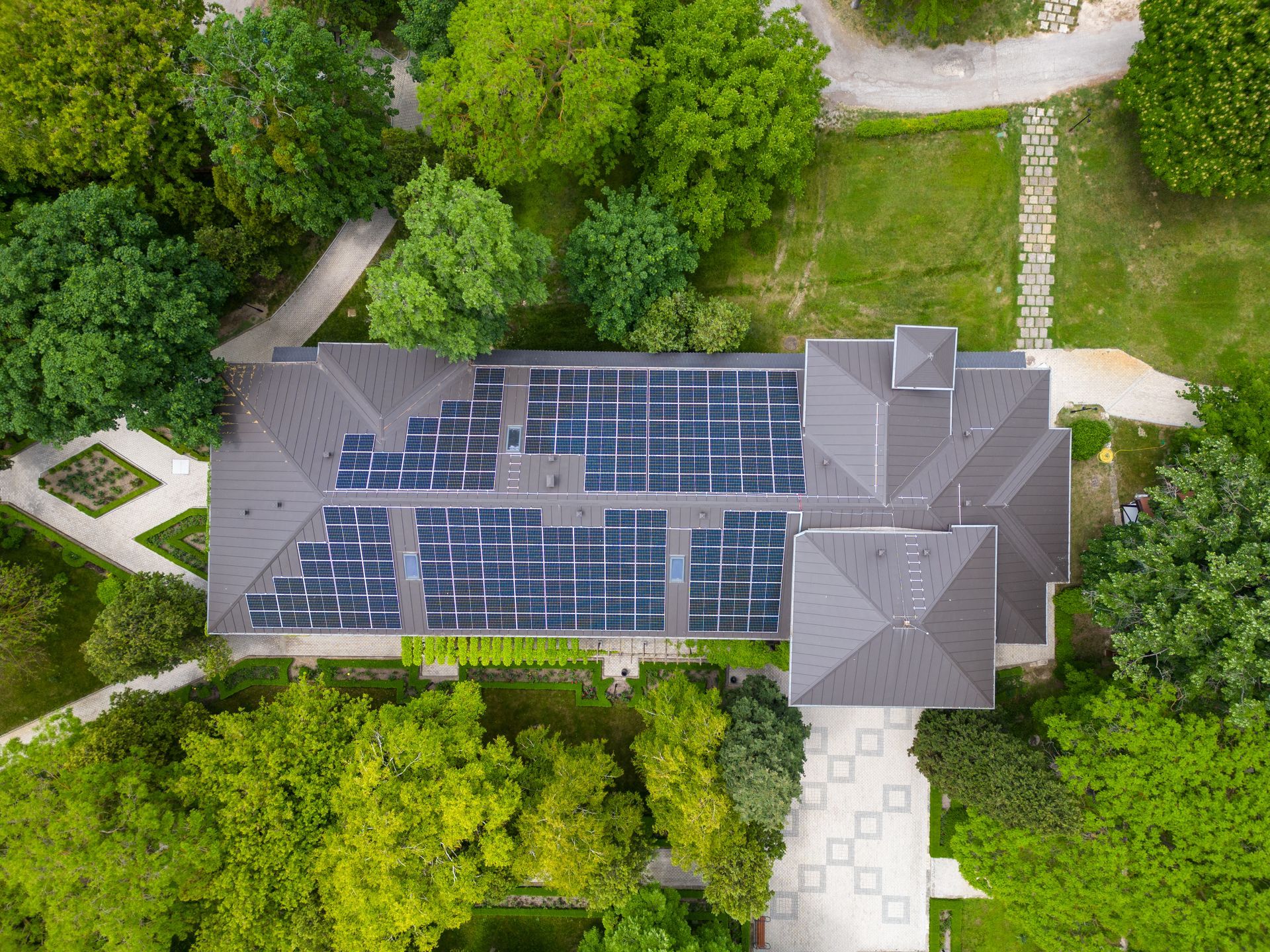 Aerial view of a building with rooftop solar panels surrounded by trees and walkways