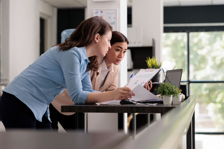 Two coworkers reviewing documents at a table in a bright office